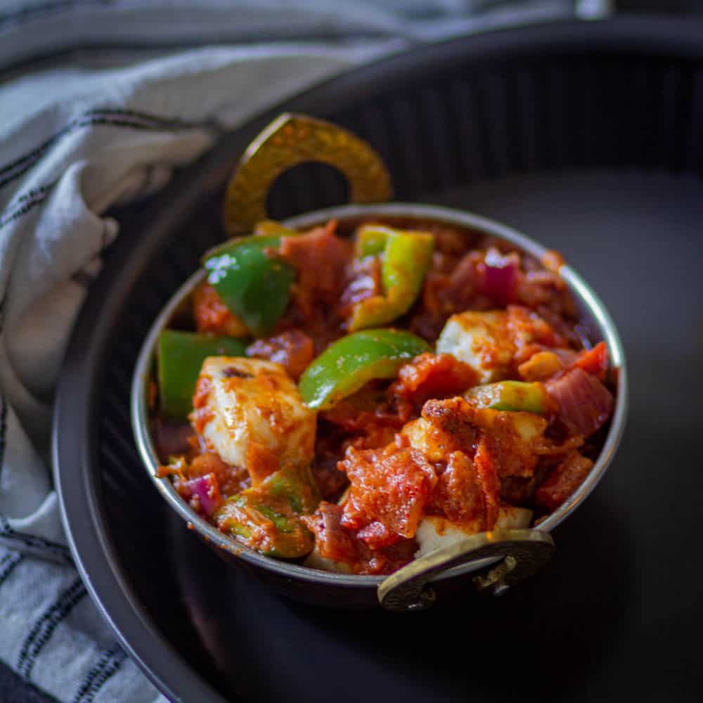 Served kadai paneer in a small wok with white linen on the background.