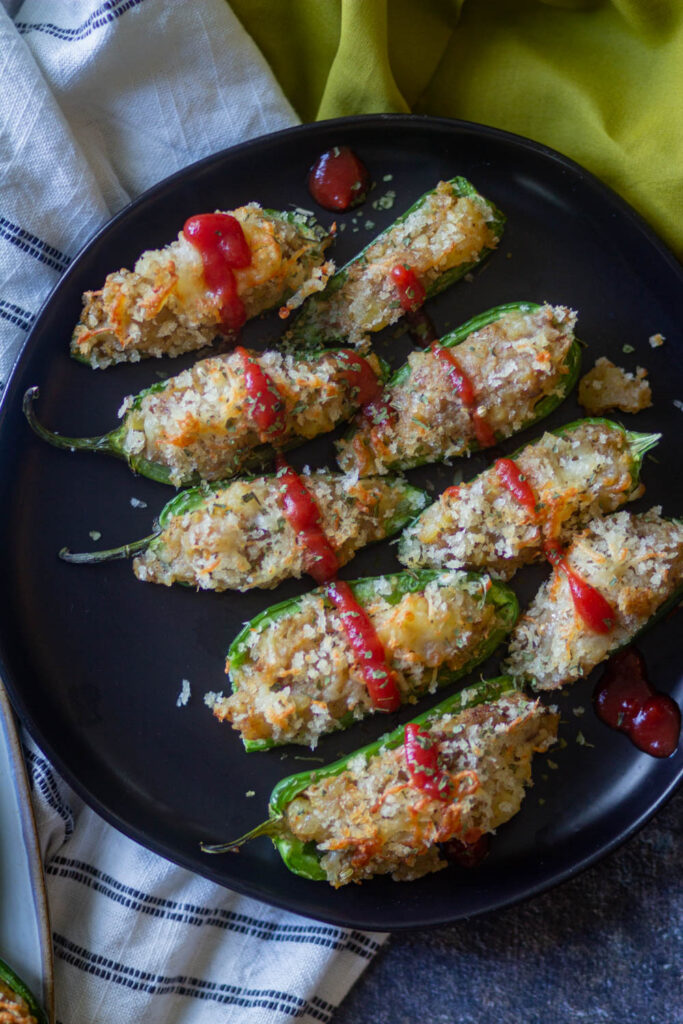 jaapeno popppers serve don a black plate with ketchup drizzle on the top