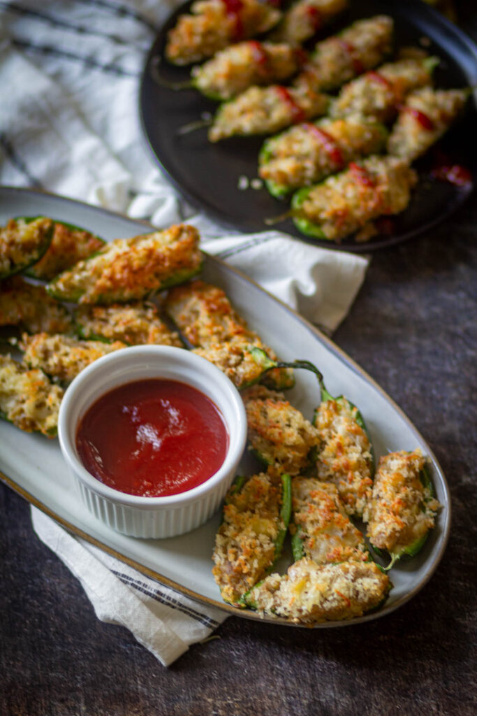 jalapeno poppers on a white plate with black plate in the background