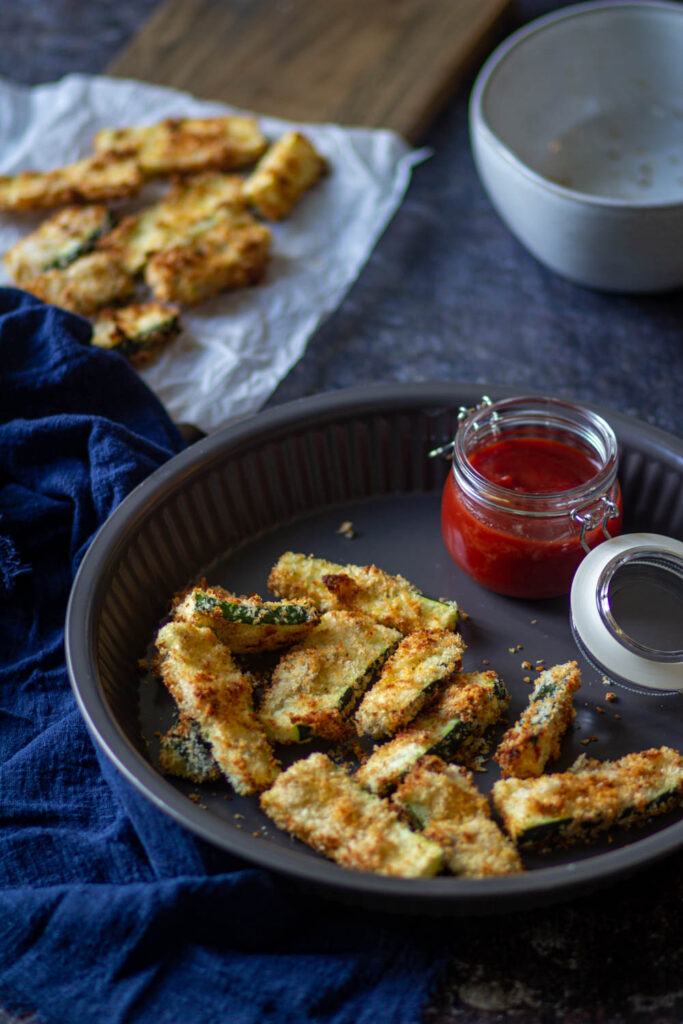 serving the zucchini fries on the gray plate with ketchup on the side