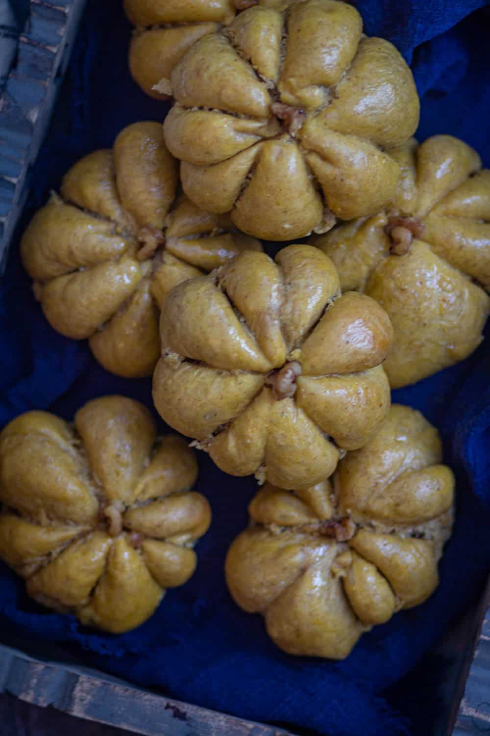 Overshot of pumpkin bread rolls over blue cloth.