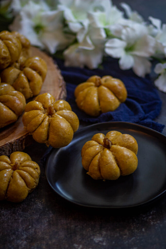 pumpkin dinner rolls one black plate.