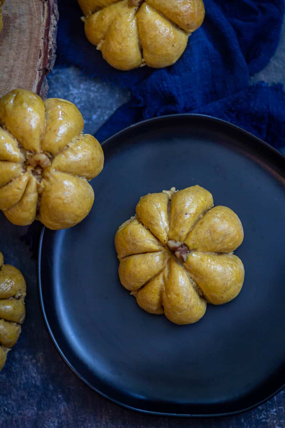 pumpkin bread rolls on a black plate.
