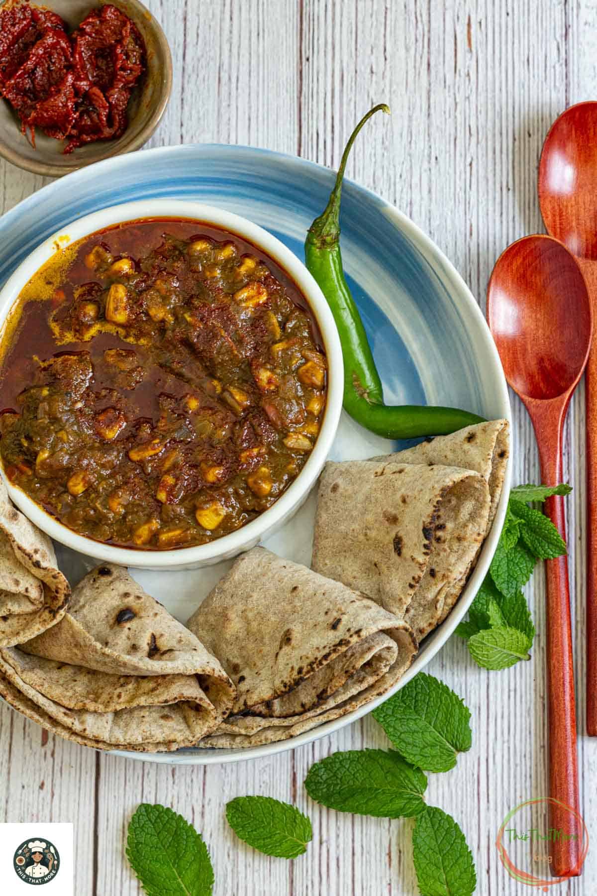 Image of a bowl of palak corns served with 4 chapatti on the white plate.