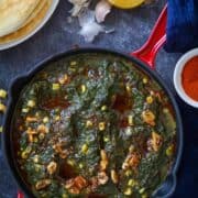 Overshot image of corn palak recipe in a red cast iron skillet served with chapatti.