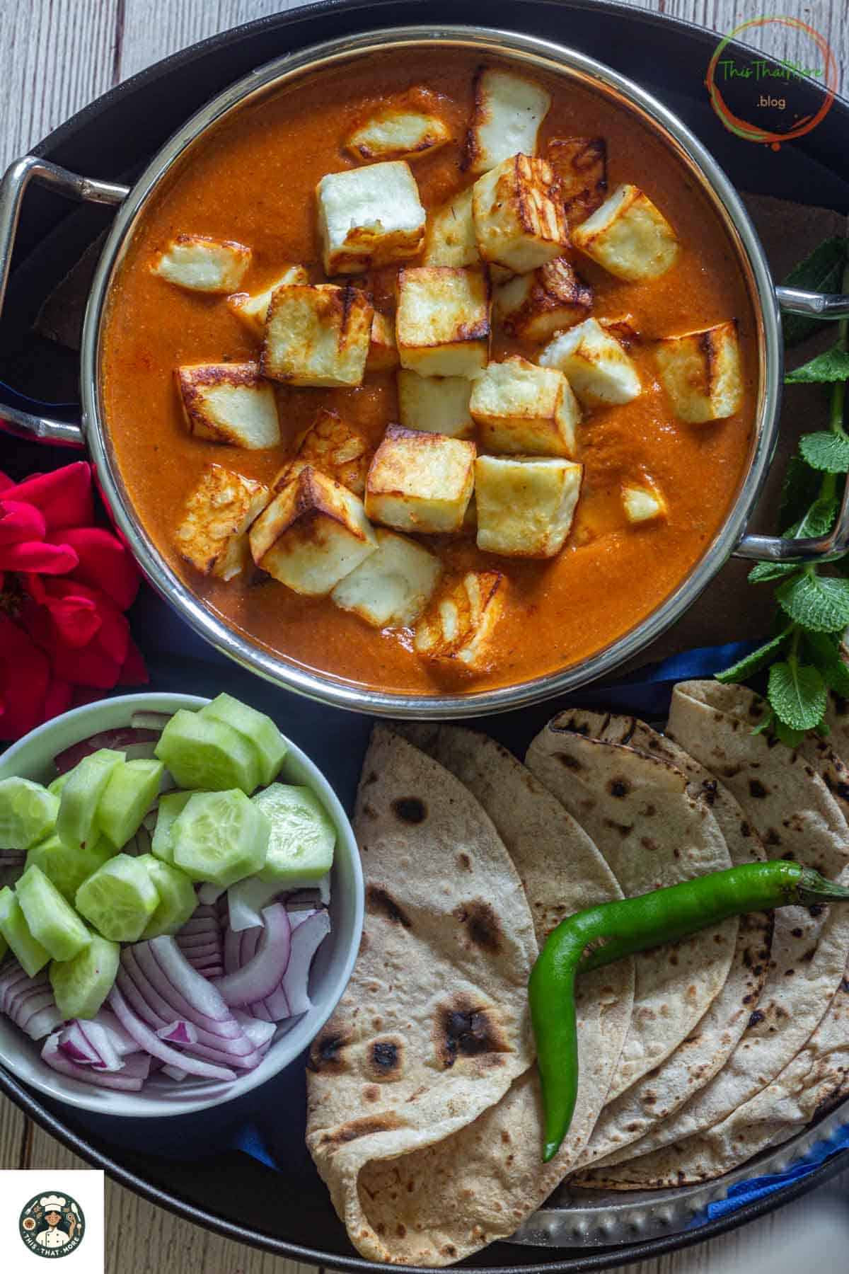 Image of shahi paneer served in a small kadai with salad and Indian flatbread.