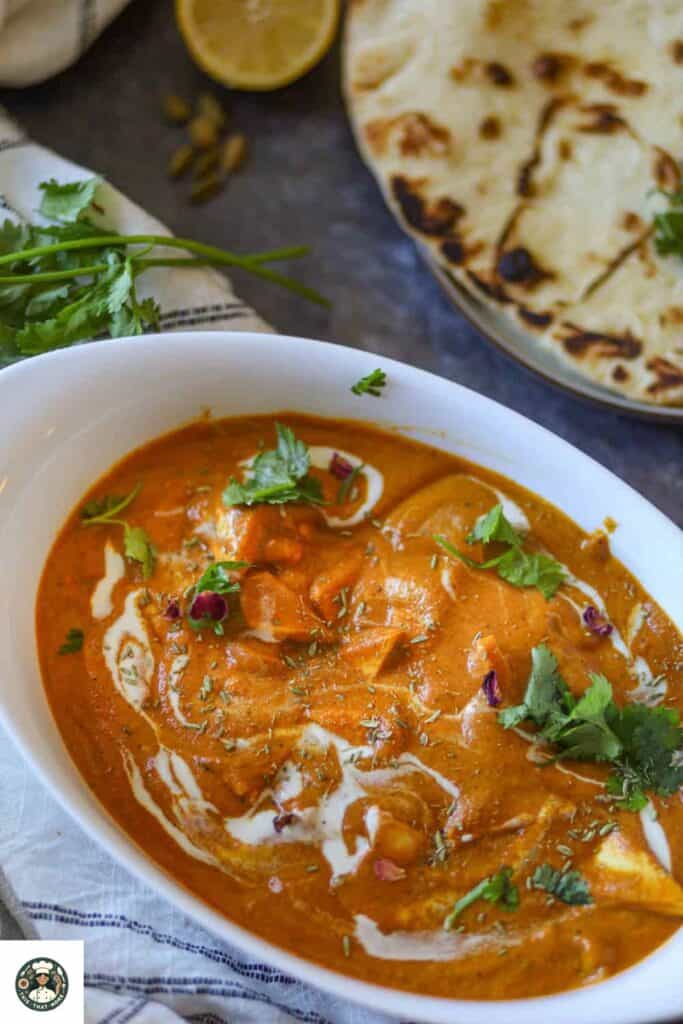 Overshot image of shahi paneer recipe in a white bowl with naan on the side.