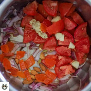 Image of pot with onion, tomatoes, ginger, garlic, and whole spices.