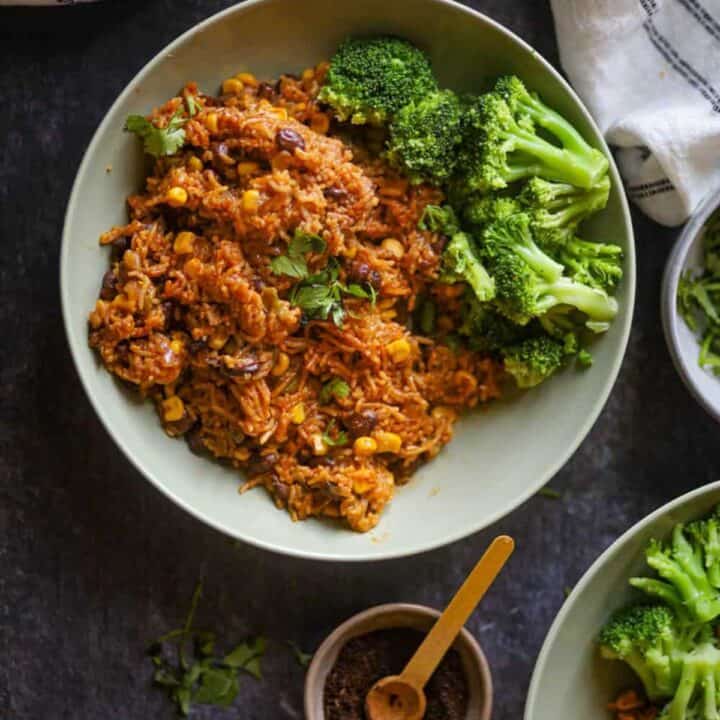 Image of Mexican Rice served in a green bowl with steamed broccoli.