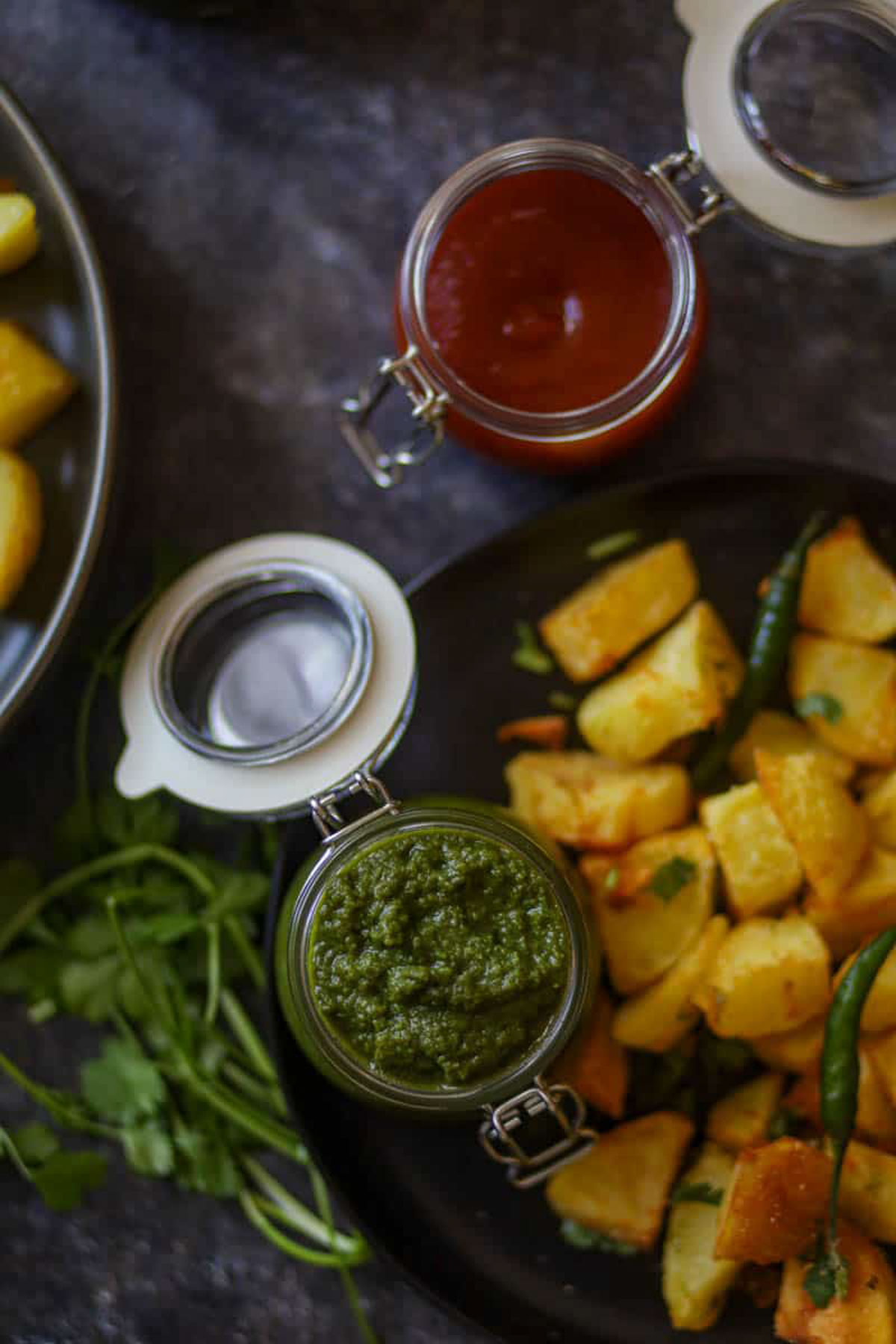 Green chutney and tamarind chutney served with Indian snacks.