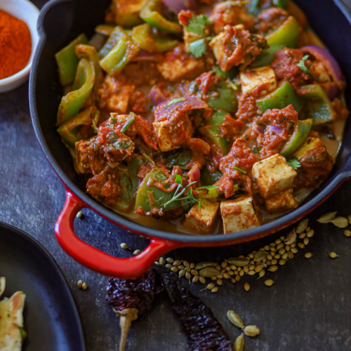 Kadai Paneer with whole spices on the background.