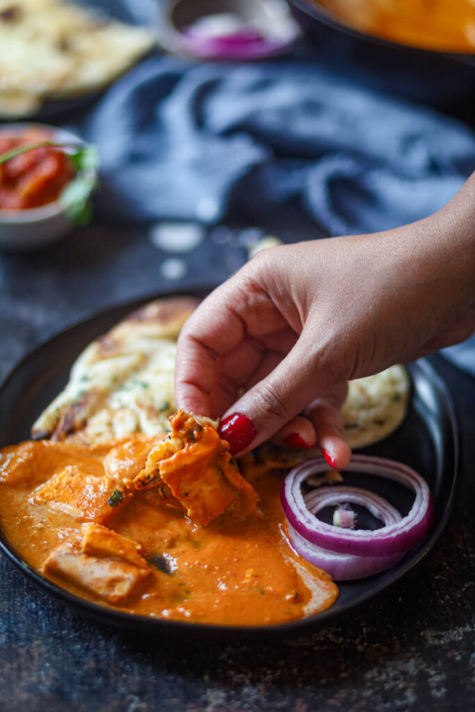 Taking a bite of butter paneer with naan.