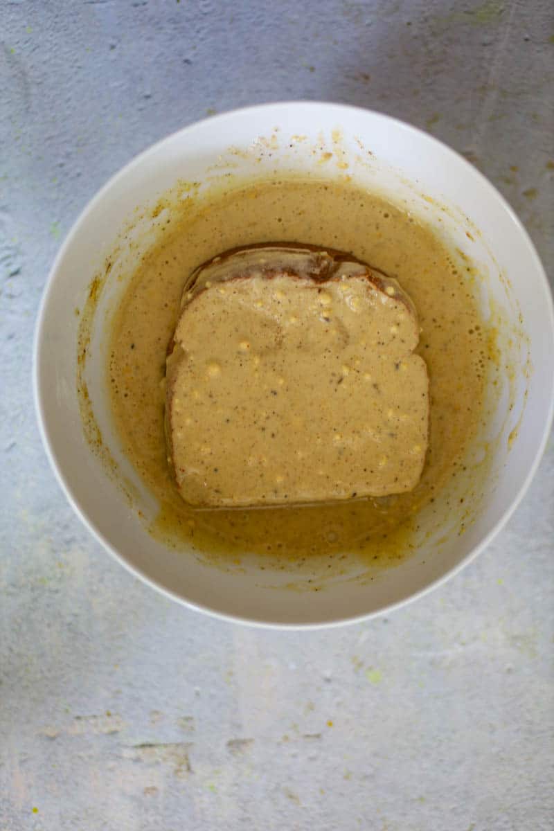 Dip the bread sandwich in the batter until it is properly coated.