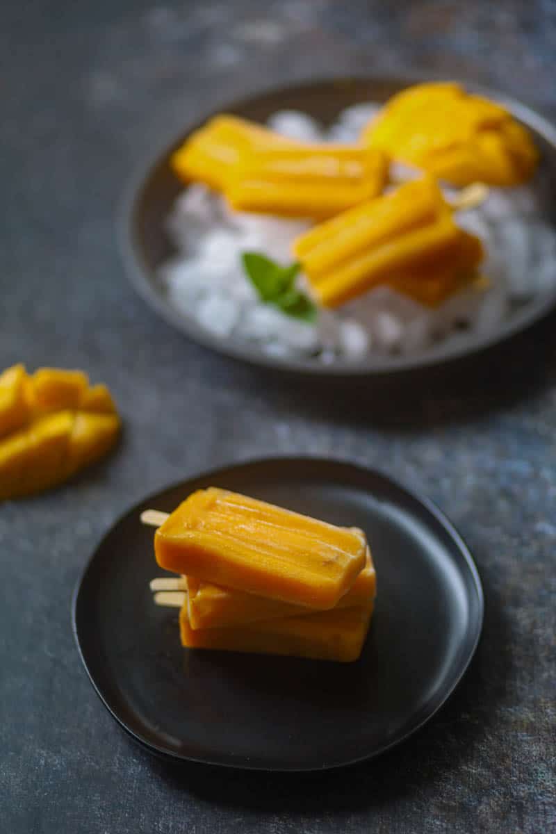 Stack of mango popsicle on a black palte.