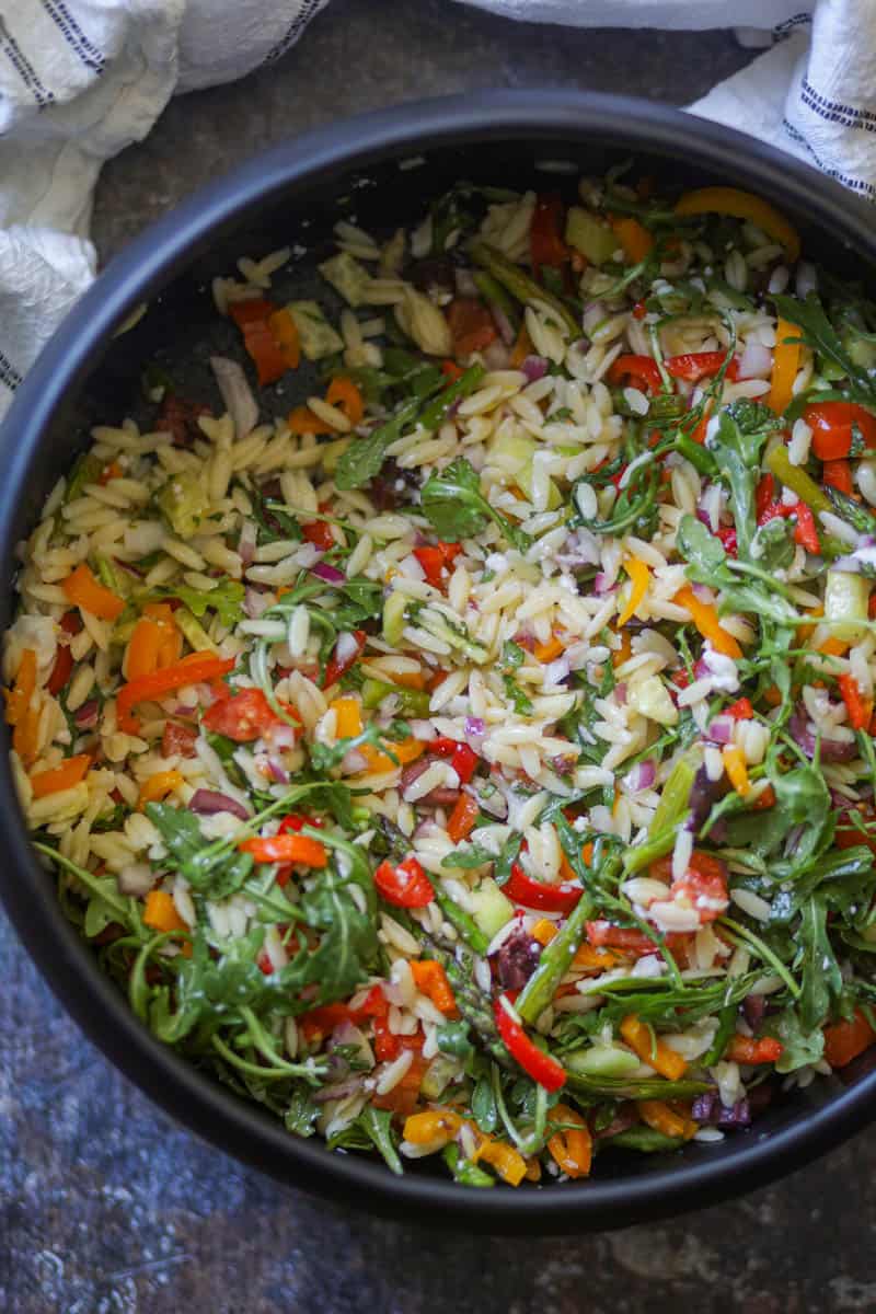 Lemon Orzo Salad with asparagus & arugula  served in a black salad bowl.