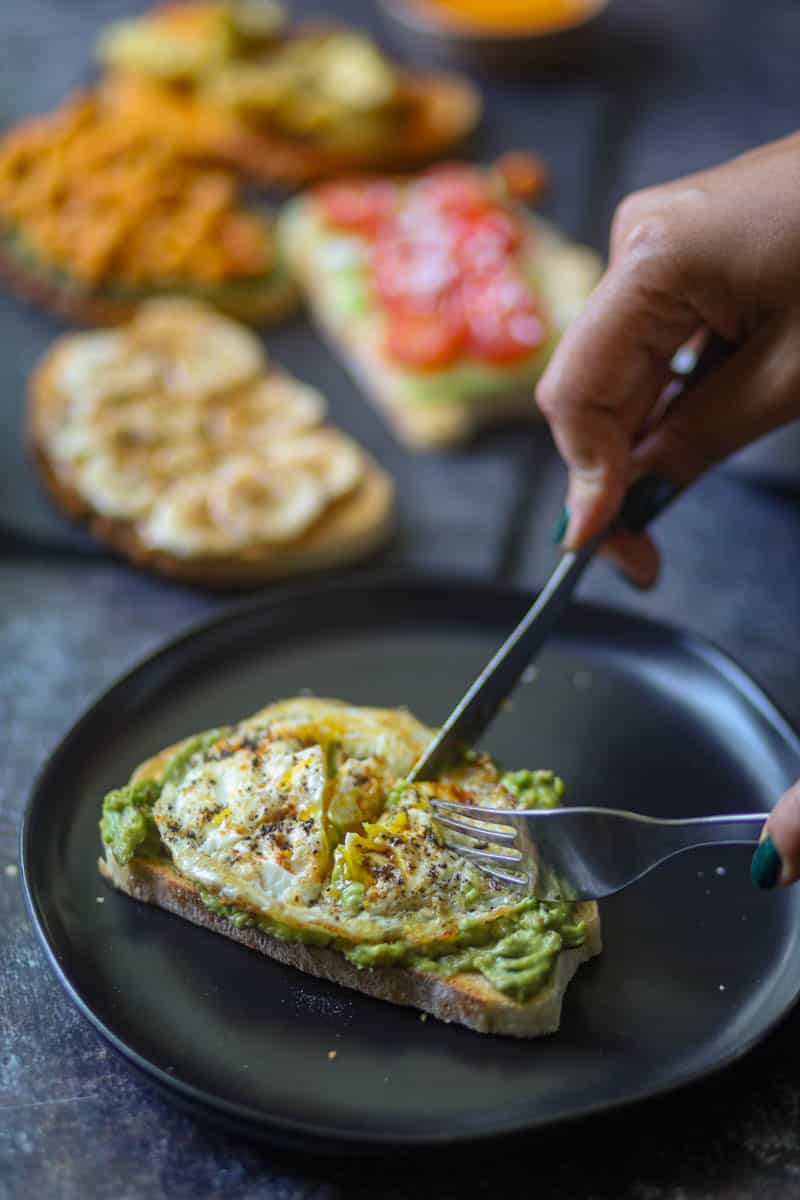 slicing the breakfast toast served with fried egg.