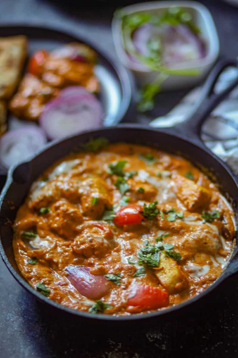 Paneer TIkka Masala served with sliced onions and green chutney.