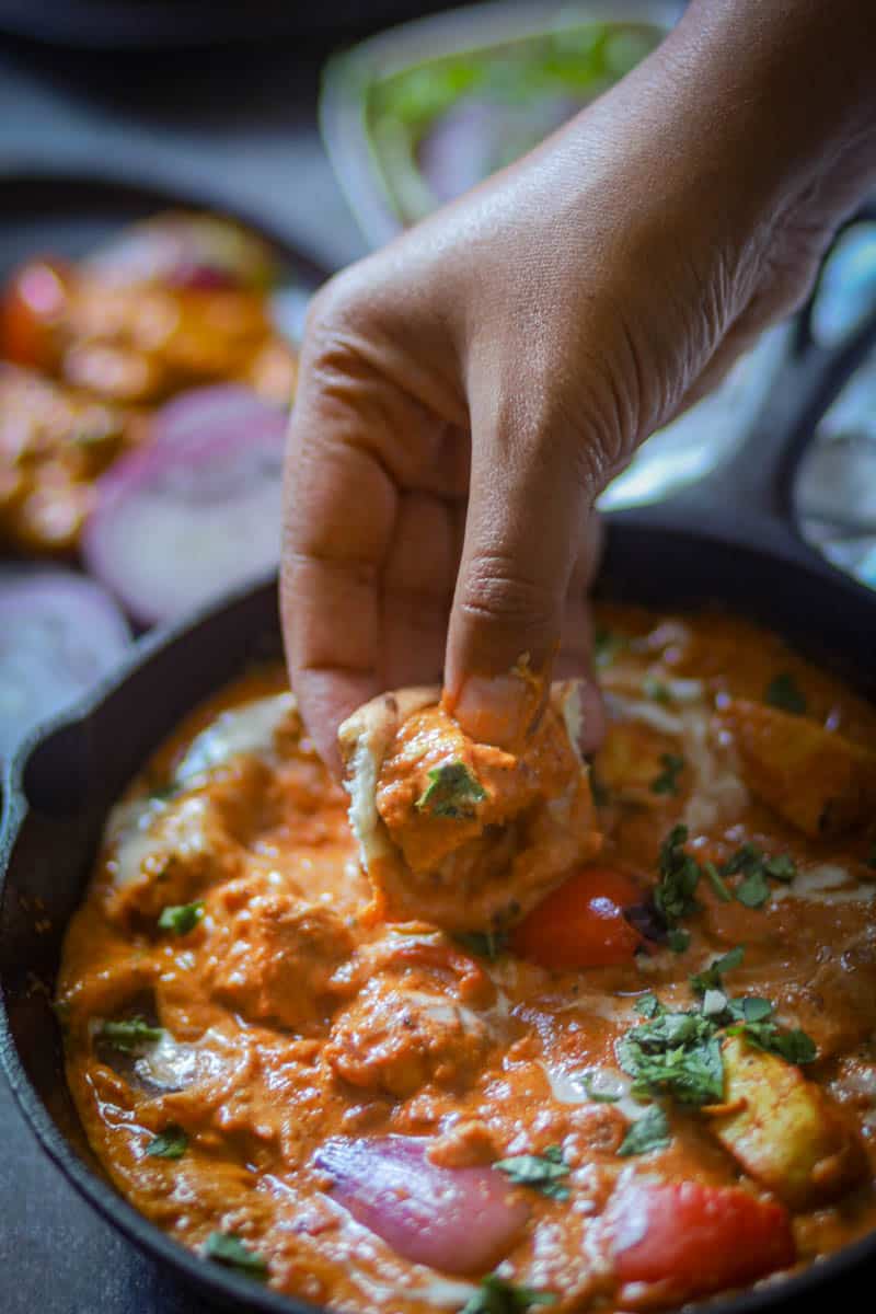 Taking  abite of paneer tikka masala gravy with naan.
