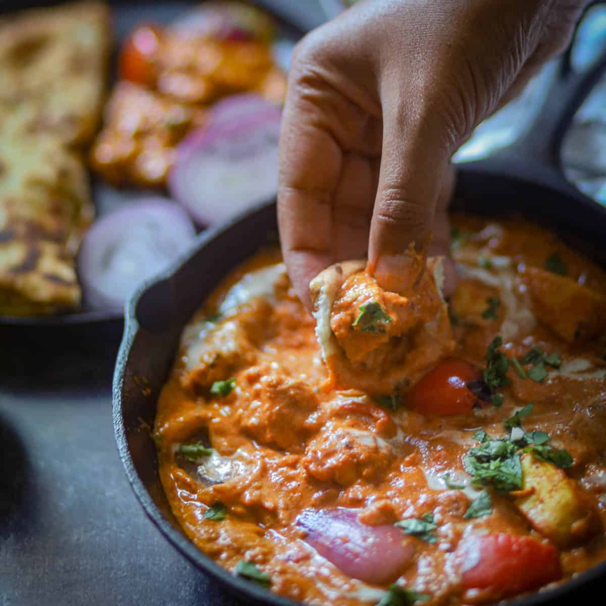Taking a bite of curry with garlic naan.