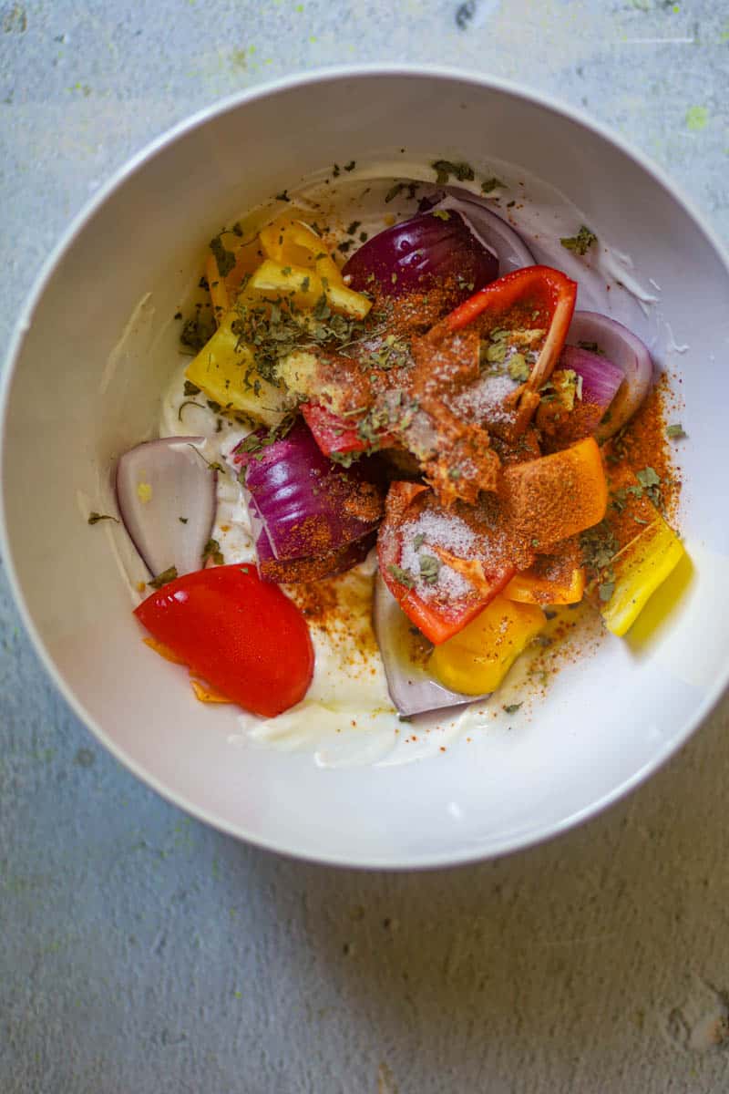 Add onions, and bell peppers in a bowl with yogurt and spices.