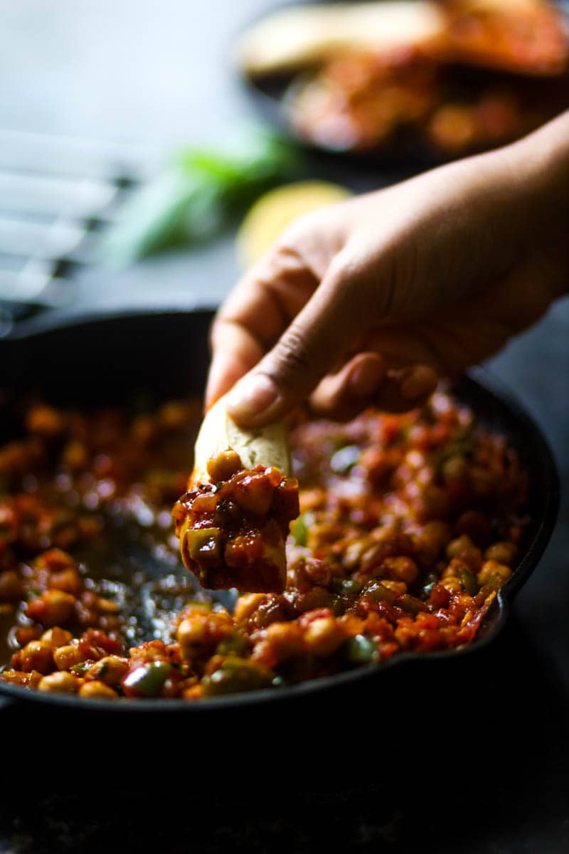 Taking a bite of vegan shakshuka with bread.