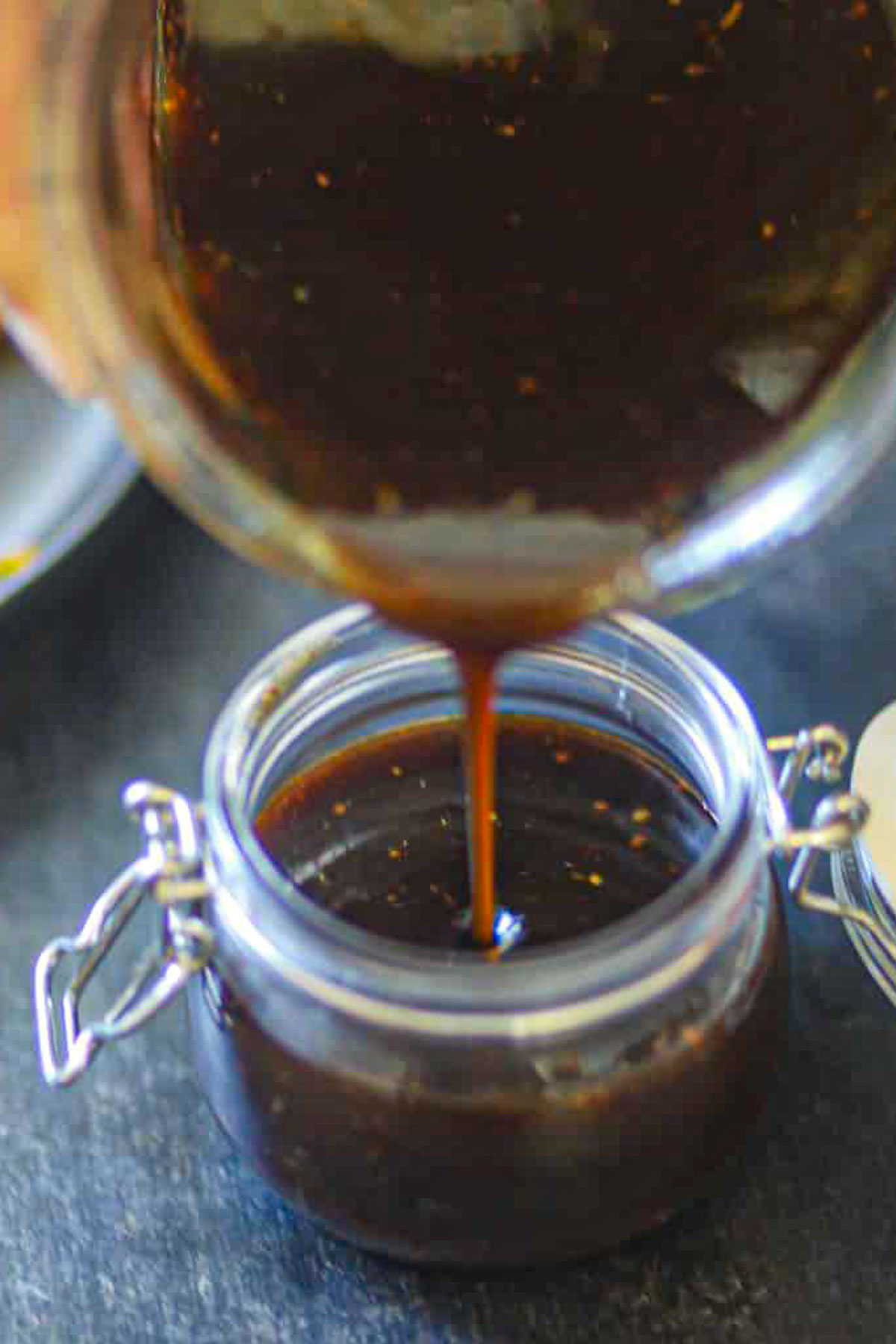 Tamarind chutney being poured into a glass jar.