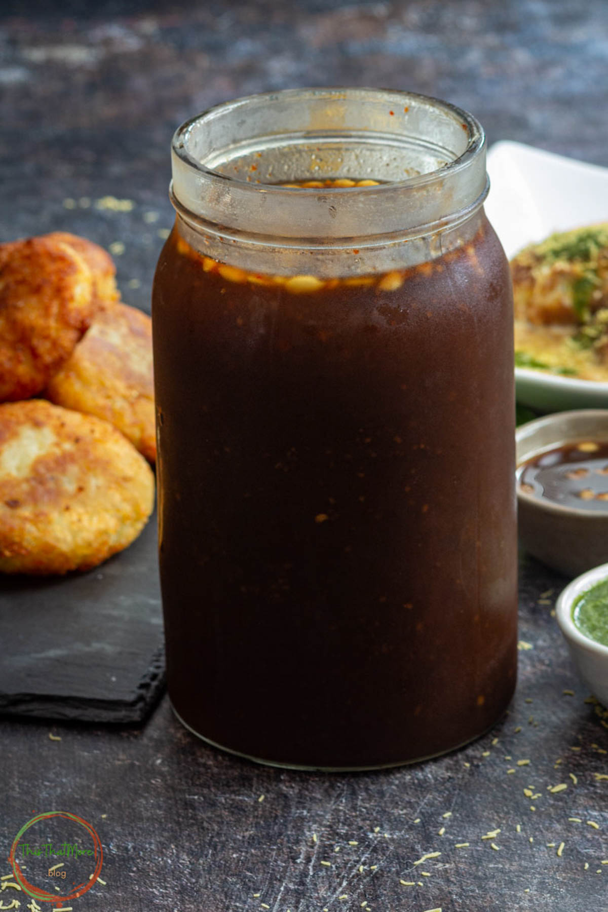 Homemade tamarind chutney in a glass jar.