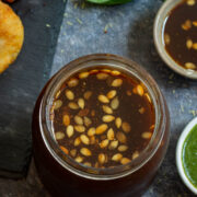 Tamarind chutney with melon seeds in a glass jar.