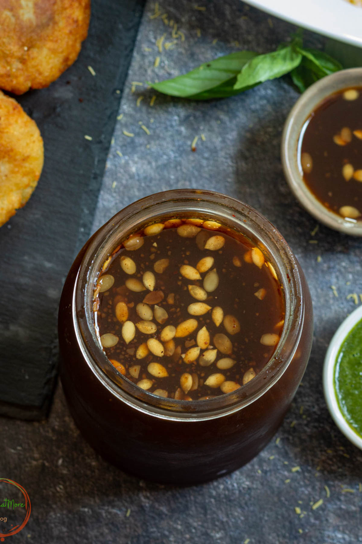 Tamarind chutney with melon seeds in a glass jar.