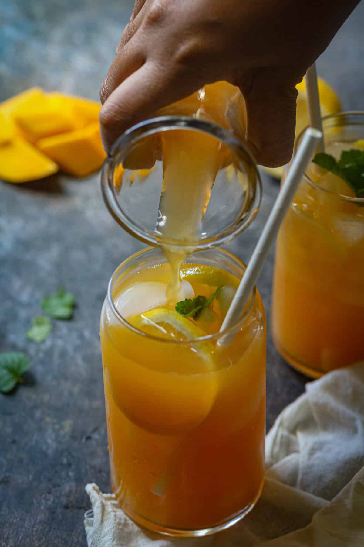 Fresh peach mango tea is poured in a tall glass over ice.