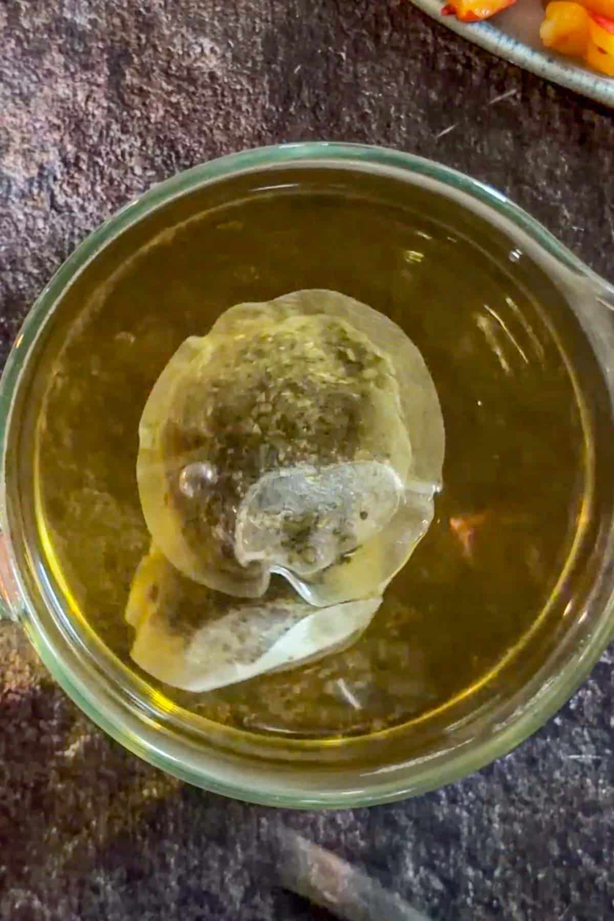 Tea bags steeping in hot water for peach mango iced tea.