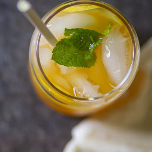 Overhead view of peach mango iced tea with ice and mint.
