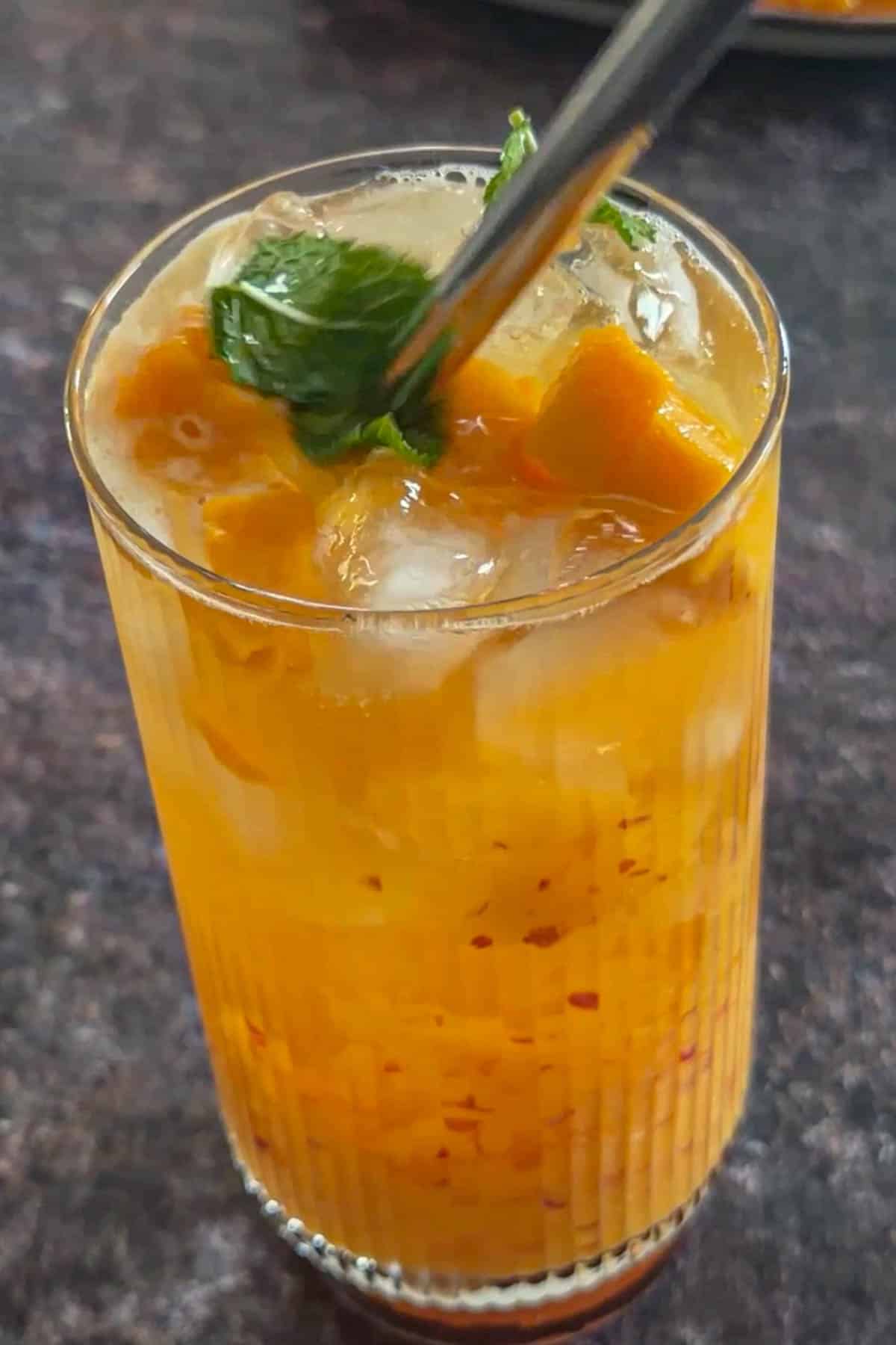 Peach mango iced tea served over ice with fresh fruit and mint.