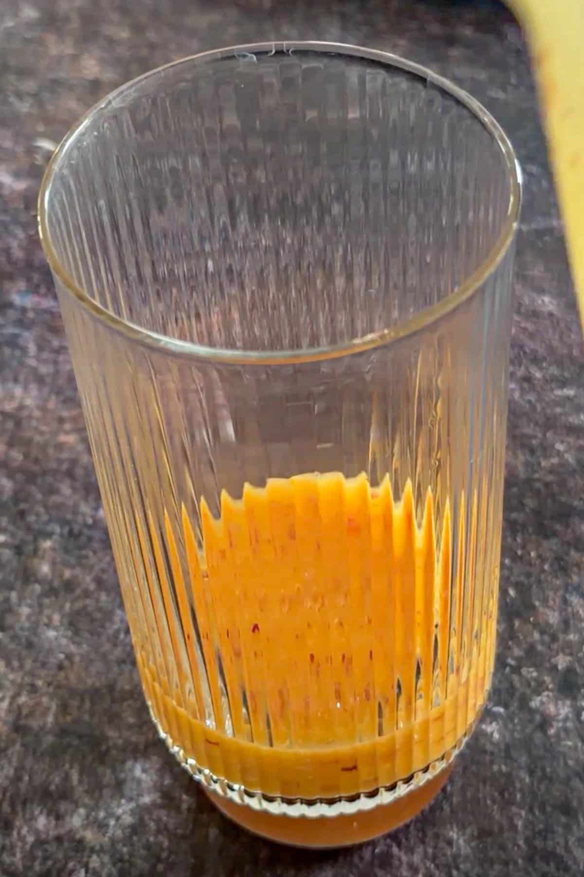 Strained peach mango puree added to the bottom of a drinking glass.