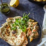 Served Navrata Curry with naan on a black plate.