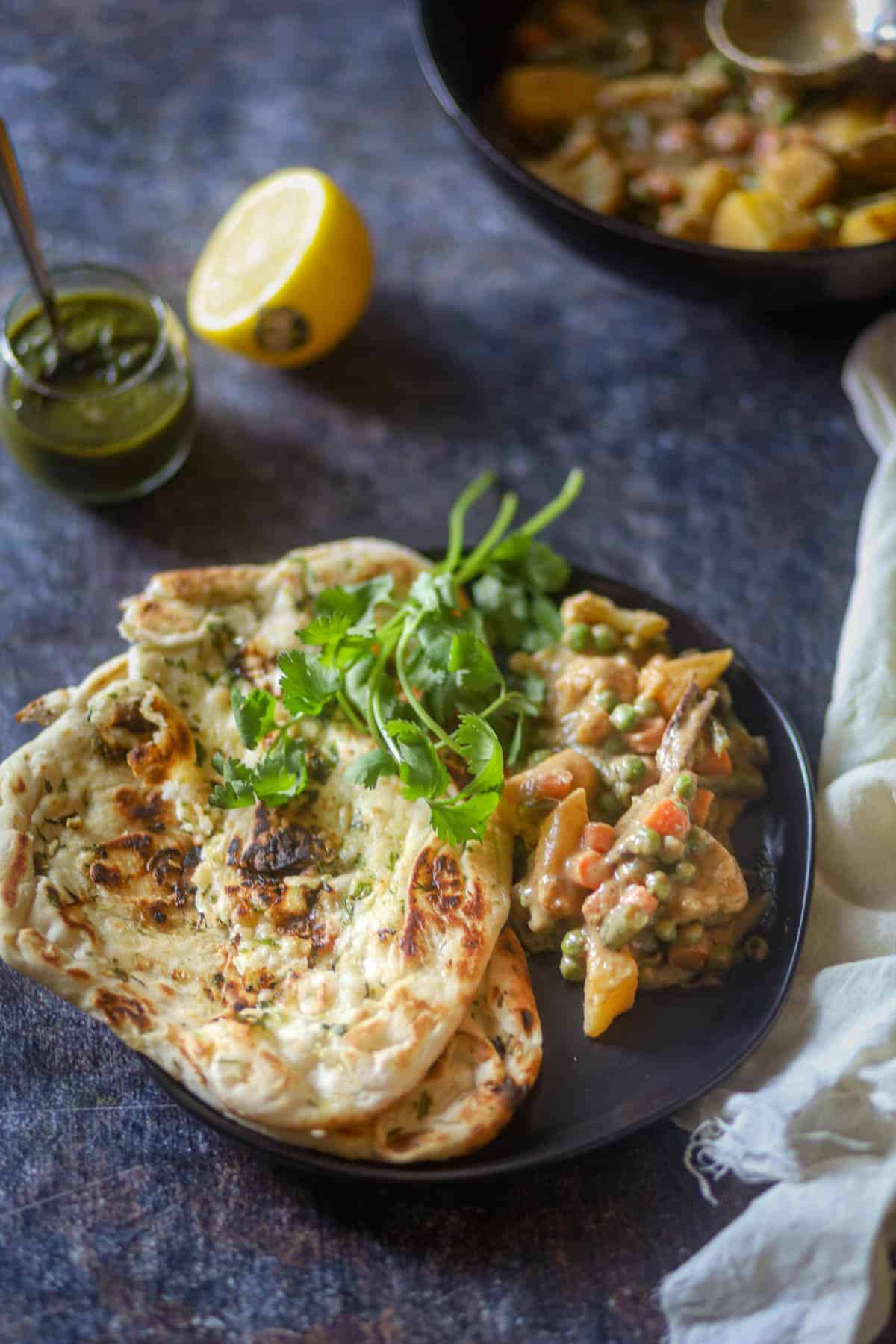 Served Navrata Curry with naan on a black plate.
