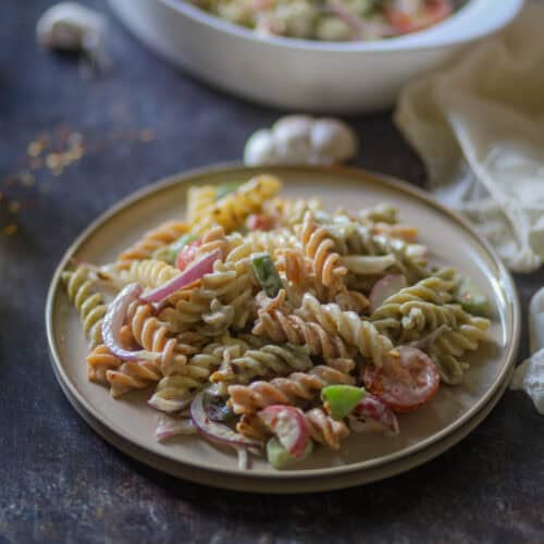 Tricolor Pasta Salad Recipe garnished with red chili flakes.