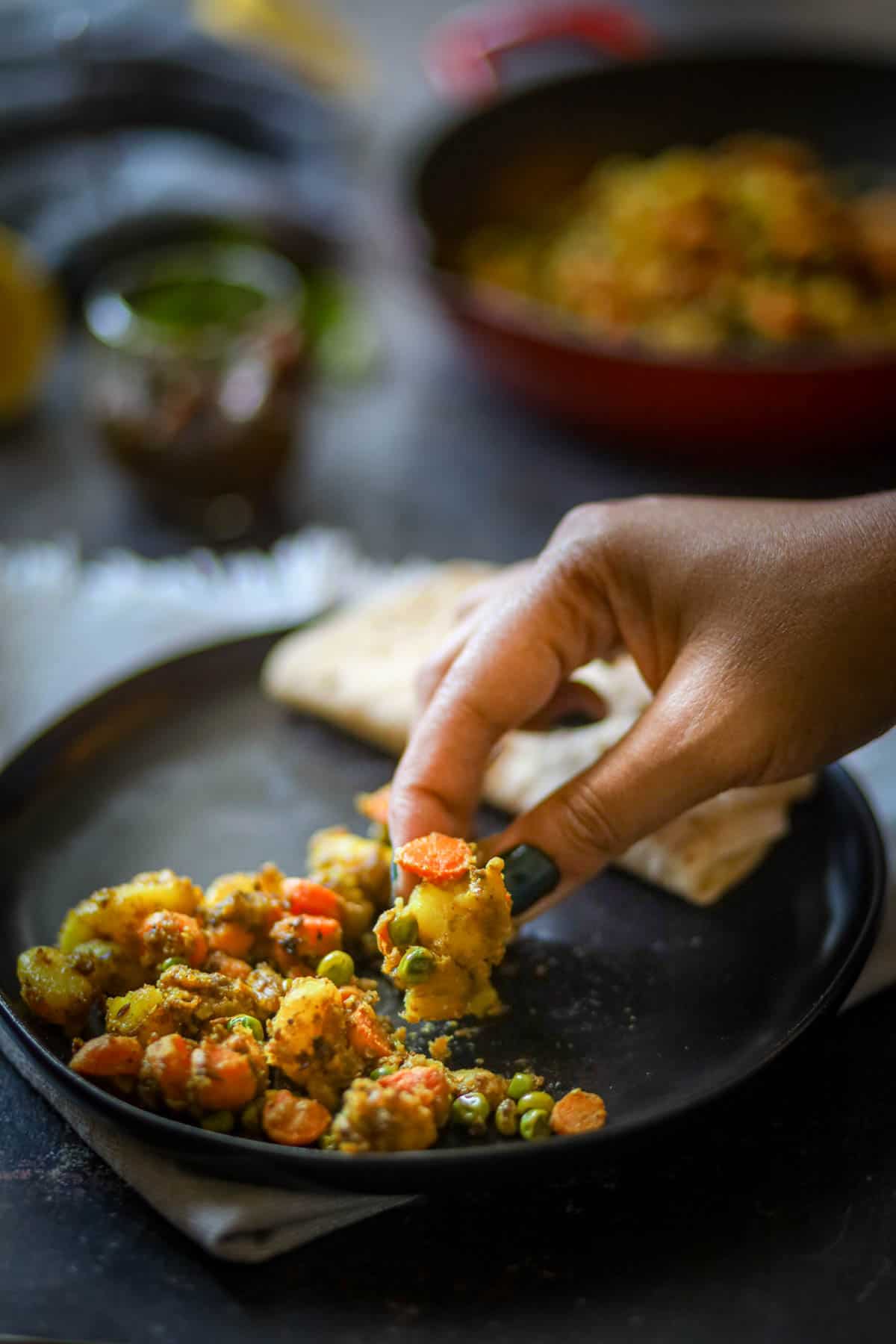 Taking a bite of aloo gajar matar with roti.