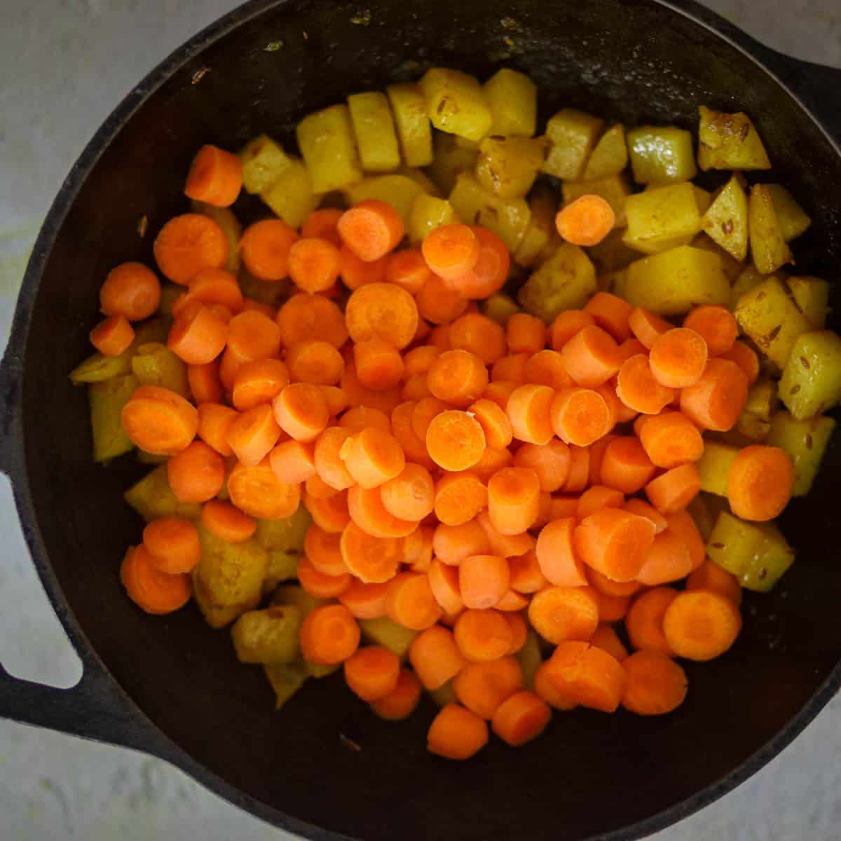 Whn potatoes are half cooked, add carrots.