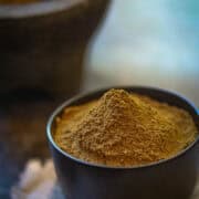 A big mountain of garam masala in a black bowl.