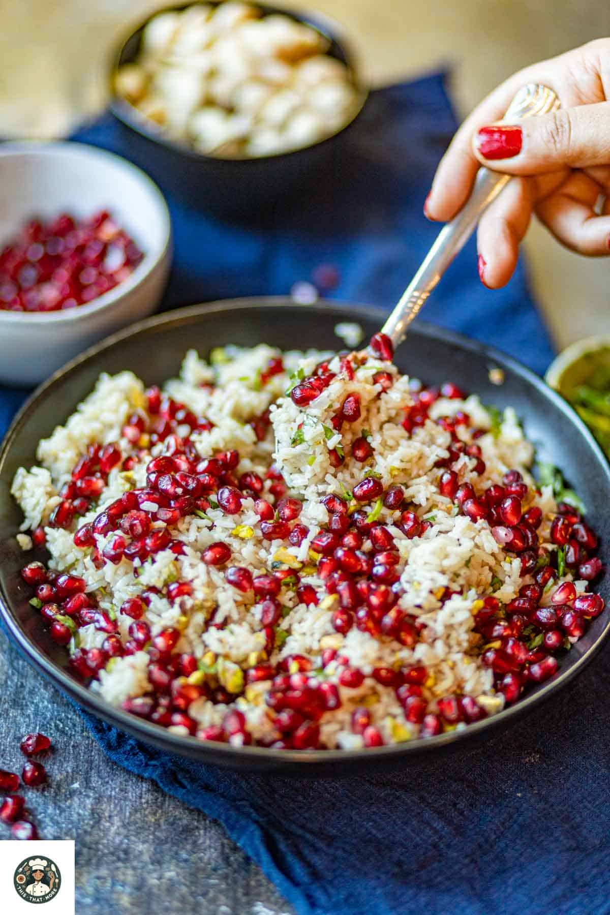 Image of a black bowl filled with pomegranate rice and a spoonful of it.