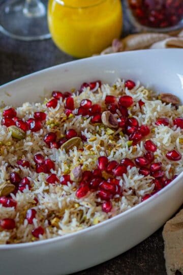 Close image of rice with pomegranate seeds in a big white bowl.