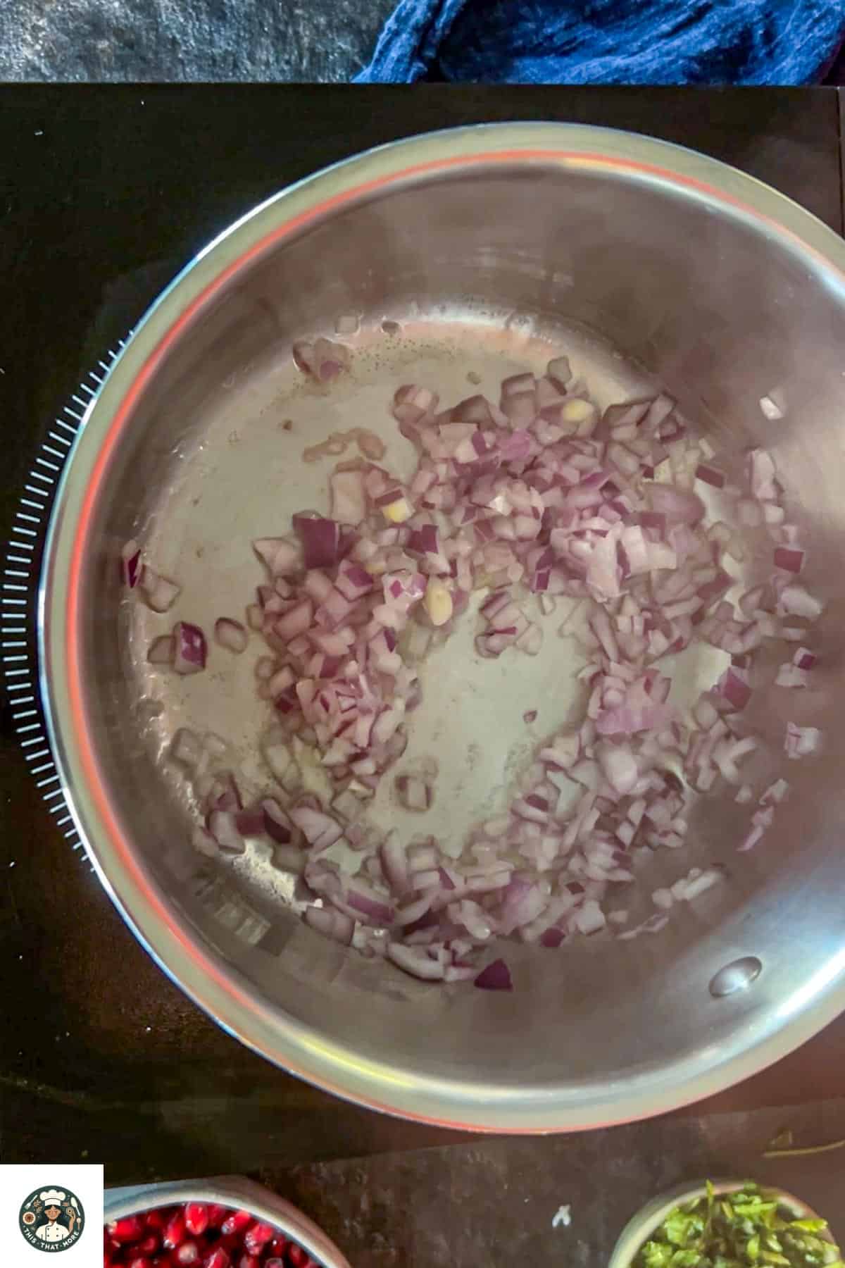 Image of a steel pot with sauteeing onions with oil and ginger.