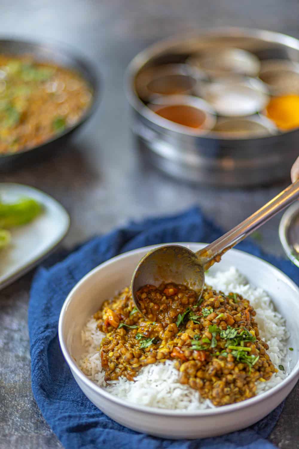 Side shot of pouring the dal over some steamed rice.