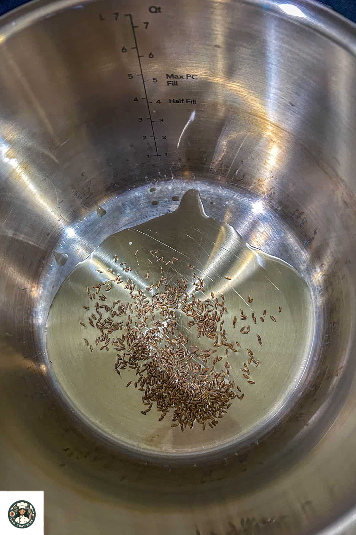 Overhead shot of a pot with oil and cumin seeds.