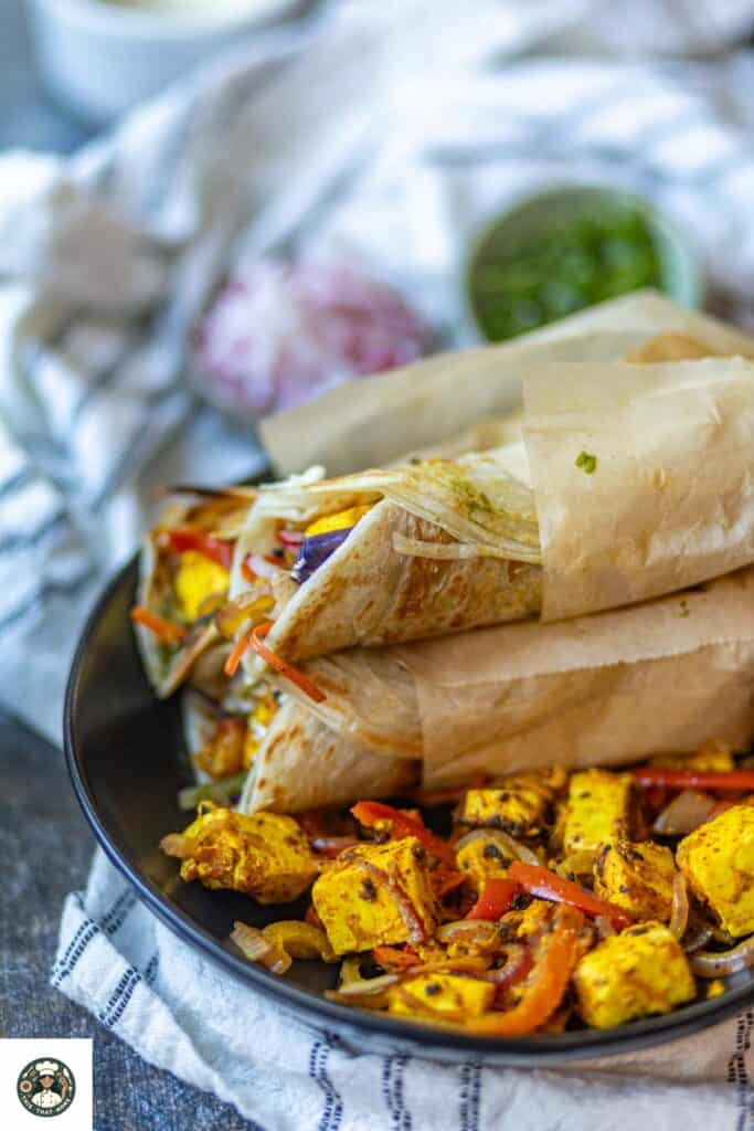 Paneer Kathi Roll served over a bowl filled with paneer stuffing.