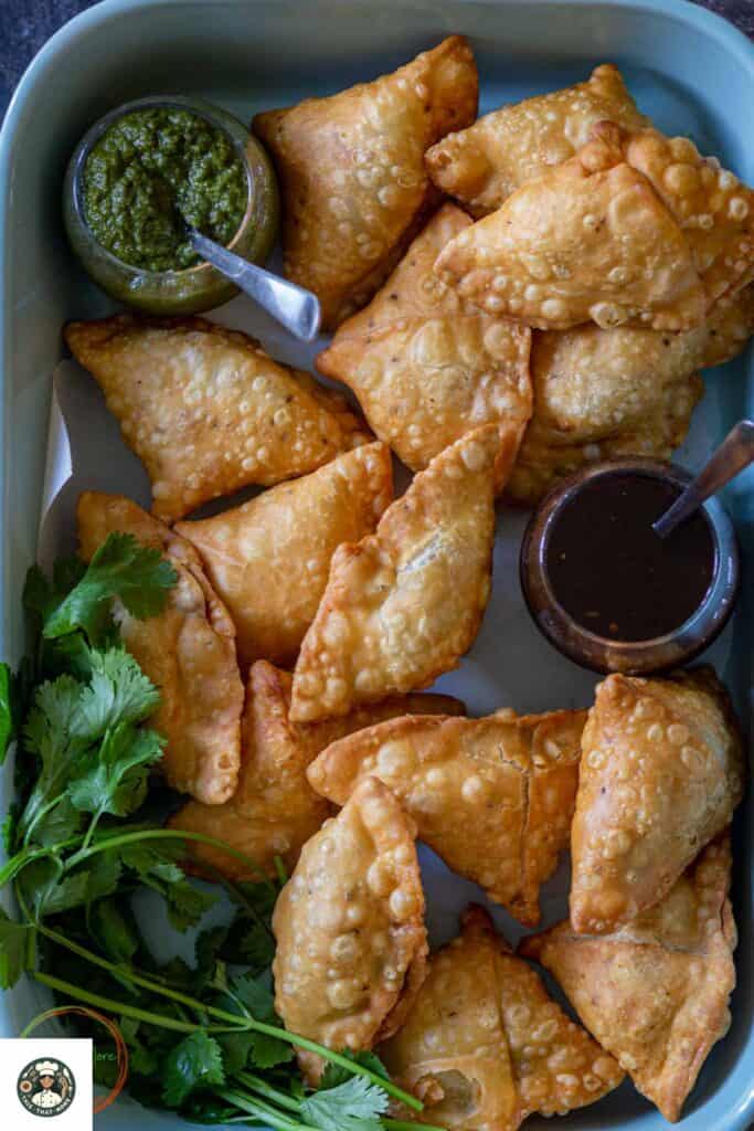 Image showing punjabi samosa served in a blue tray with chutney.