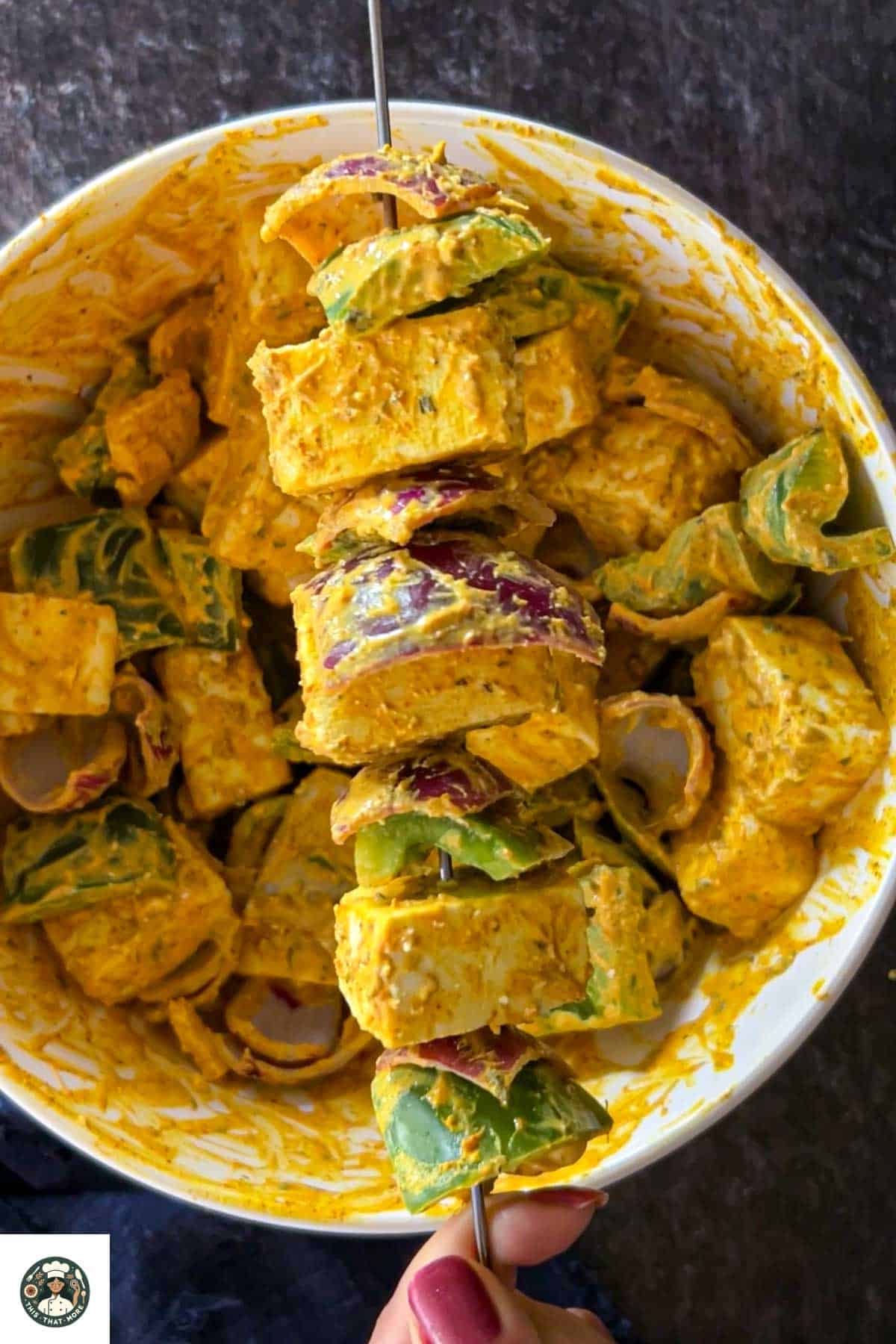 Image showing alternating the onion, bell peppers, and paneer in a steel skewer for making paneer tikka.