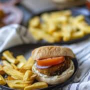 Aloo Tikki Burger served with potato fries on a black plate.