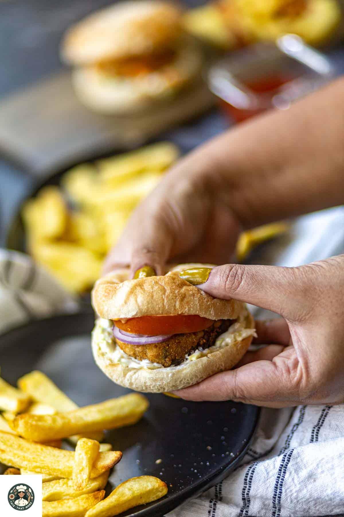 Holding soft burger aloo tikki in hand.